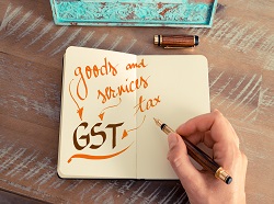 Retro effect and toned image of a woman hand writing a note with a fountain pen on a notebook. Handwritten text GST GOODS AND SERVICES TAX business success concept