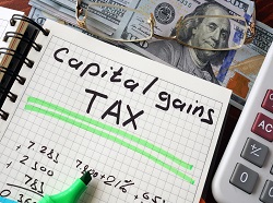 Notebook with capital gains tax sign on a table. Business concept.