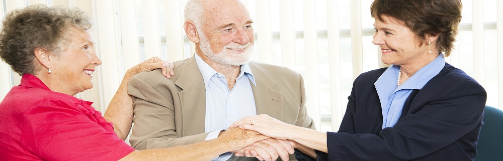 Senior couple shakes hands with their financial advisor or broker.
